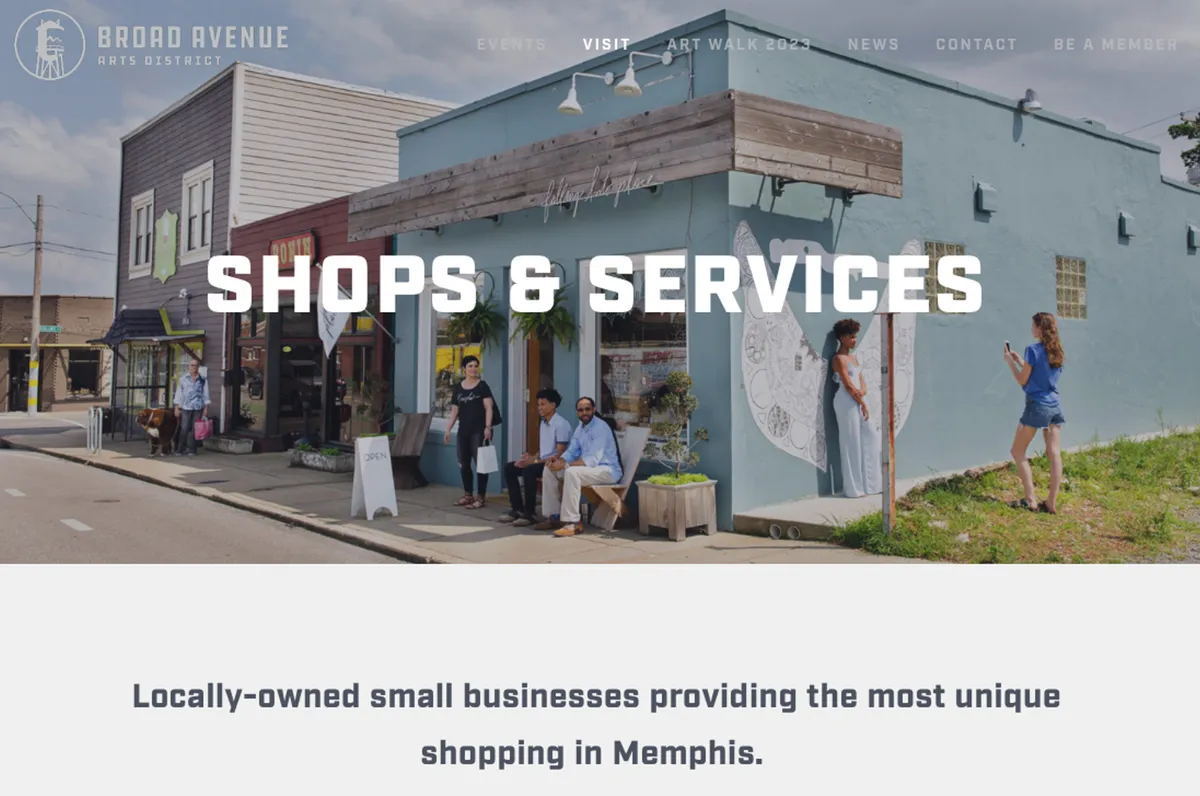 A lively streetscape with colorful storefronts, people chatting on the sidewalk, and vibrant local artwork decorating the walls. The scene captures the energy and creative spirit of the surrounding Memphis neighborhood, suggesting easy access to coffee shops, unique stores, and community life.