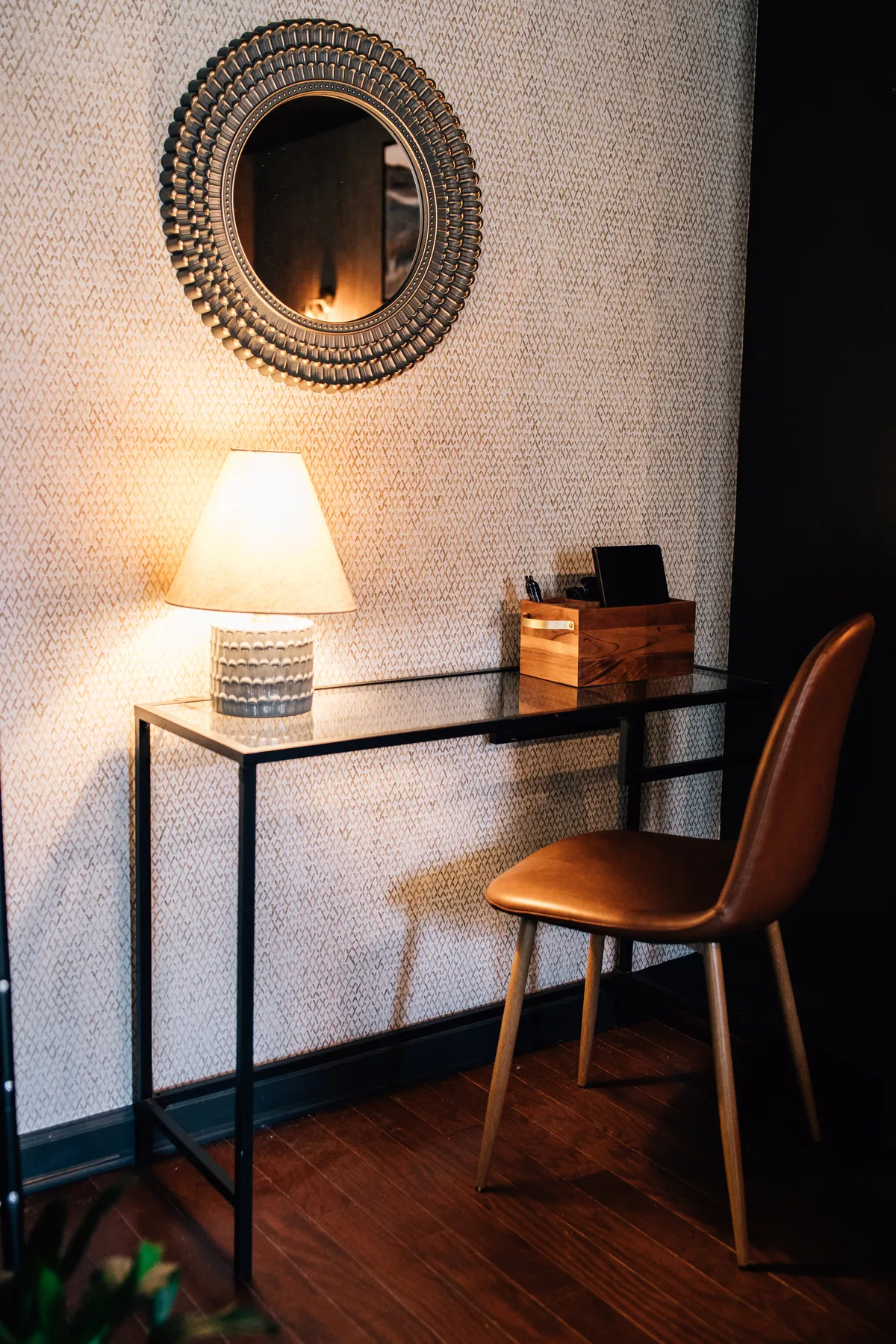 A cozy desk setup featuring a lamp for focused work, a stylish mirror reflecting soft light, and a wooden box that adds both function and artistic charm. The workspace is inviting, designed for activities like reading, writing, or studying. Artistic accents and neutral tones complement the modern studio aesthetic.