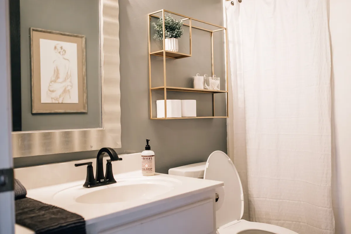 A serene bathroom view centered on a mirror and sink with decorative shelving. The scene highlights the space's potential for peaceful personal grooming and self-care, with subtle decor enhancing the sense of calm.