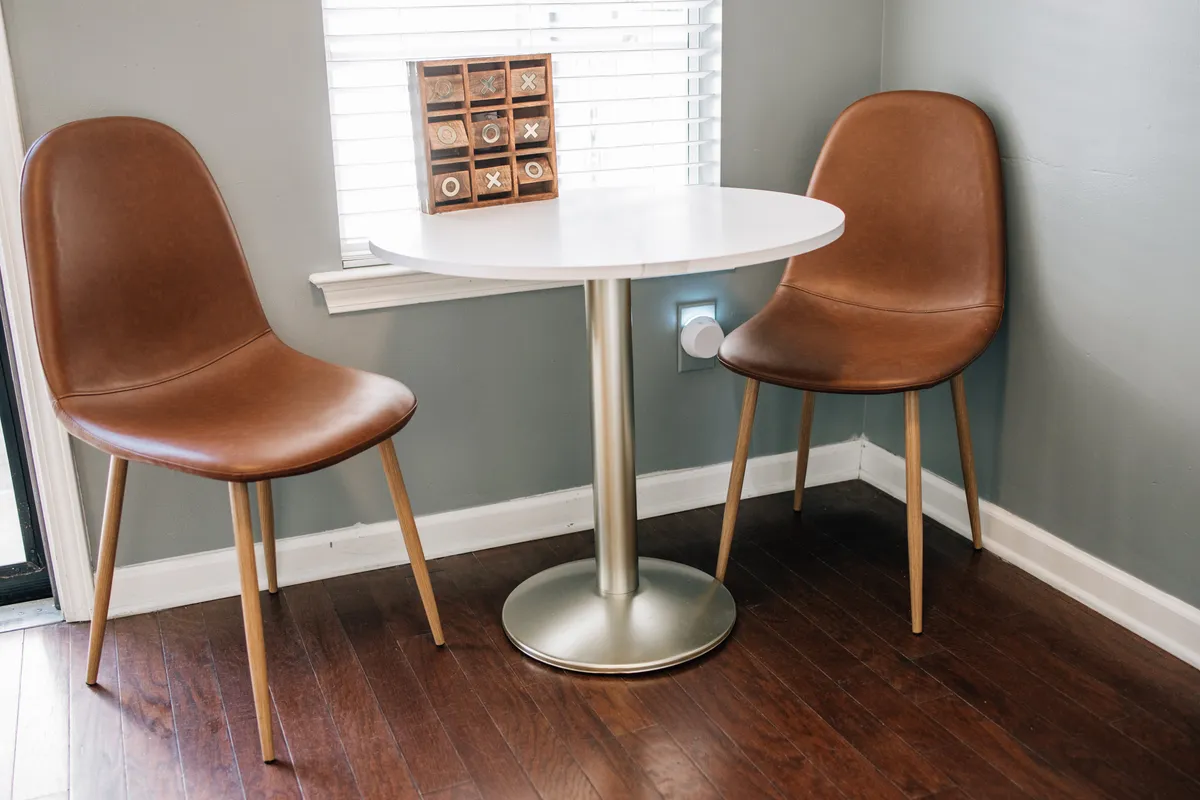 A round table with two brown chairs is set up for a casual game of tic-tac-toe, suggesting a friendly and inviting space for conversation or a quick game. The scene feels communal, ideal for solo travelers looking to connect or enjoy a quiet moment after a day in the city.